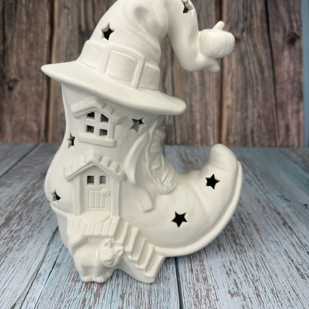 White ceramic witch boot with hat on a wooden surface