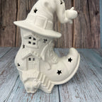 White ceramic witch boot with hat on a wooden surface