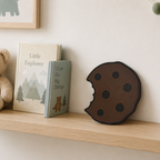 Shelf with teddy bear, books, and a decorative cookie-shaped object against a light wall.