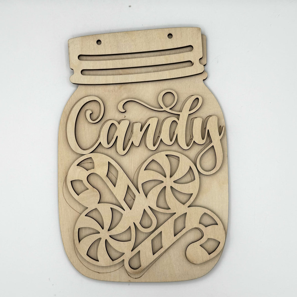 A laser-cut wooden Christmas sign shaped like a mason jar with the word 'Candy' in script and two candy cane illustrations, shown on a plain white background.
