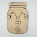 A laser-cut wooden jester mask or decorative plaque shaped like a mason jar, made from light natural wood with cutout facial features and two button details, shown on a plain light background.