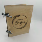 Wooden box with 'Cards of Christmas Past' text and decorative ribbons on a white background