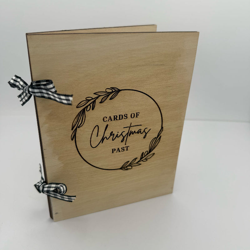 Wooden box with 'Cards of Christmas Past' text and decorative ribbons on a white background