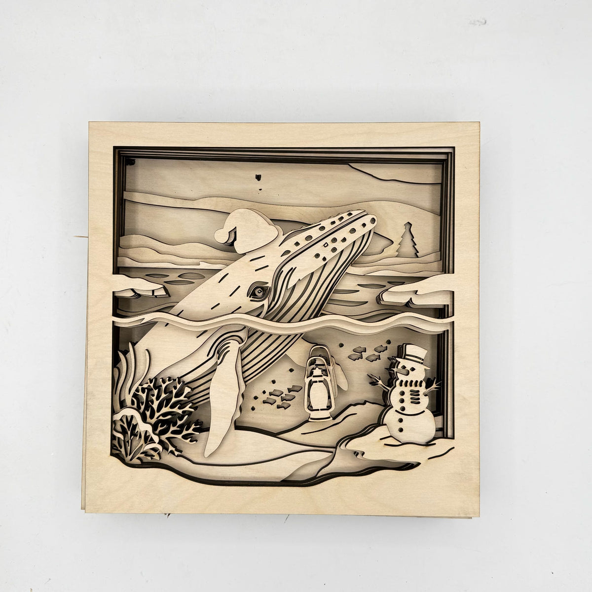 A square wooden laser-cut box featuring a 3D layered scene of a whale, penguins, a snowman, and coral reefs, displayed on a clean white background.