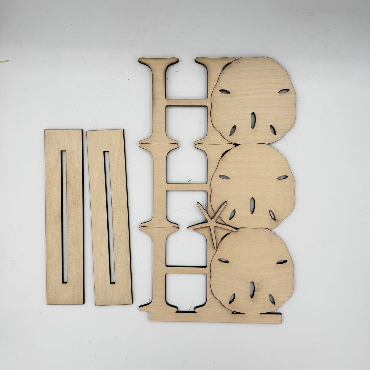 Laser-cut wooden decorative letter H with sand dollar and starfish cutouts, shown with two separate rectangular wooden pieces on a plain white background.