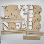 Laser-cut wooden Christmas decorations spelling out 'JOY NOEL HAP' with star accents and shell motifs, arranged on a white background.