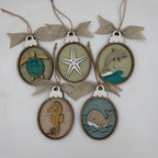 Six oval wooden hanging ornaments with burlap bows, each featuring a different nautical design: a turtle, starfish, dolphin, seahorse, and whale. The ornaments are arranged on a plain white background.