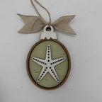 A round wooden hanging ornament with a natural wood frame, a pale green center, and a white starfish design in the middle. The ornament is suspended by a twine string and tied with a beige burlap bow at the top, shown against a plain white background.
