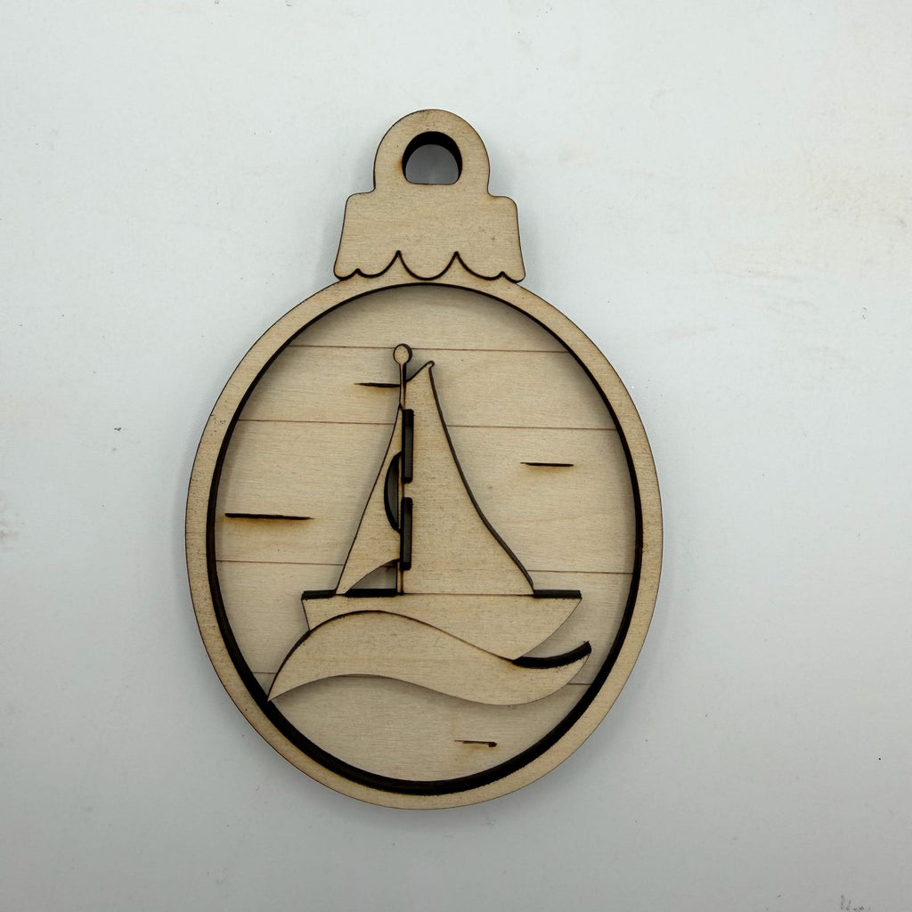 A laser-cut wooden ornament or tag featuring a sailboat design inside an oval frame with a hanging loop at the top, shown on a plain light background.
