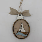 A wooden oval hanging ornament featuring a sailboat design with a light wood sail, brown hull, and light blue wave, suspended from a beige burlap ribbon on a white background.