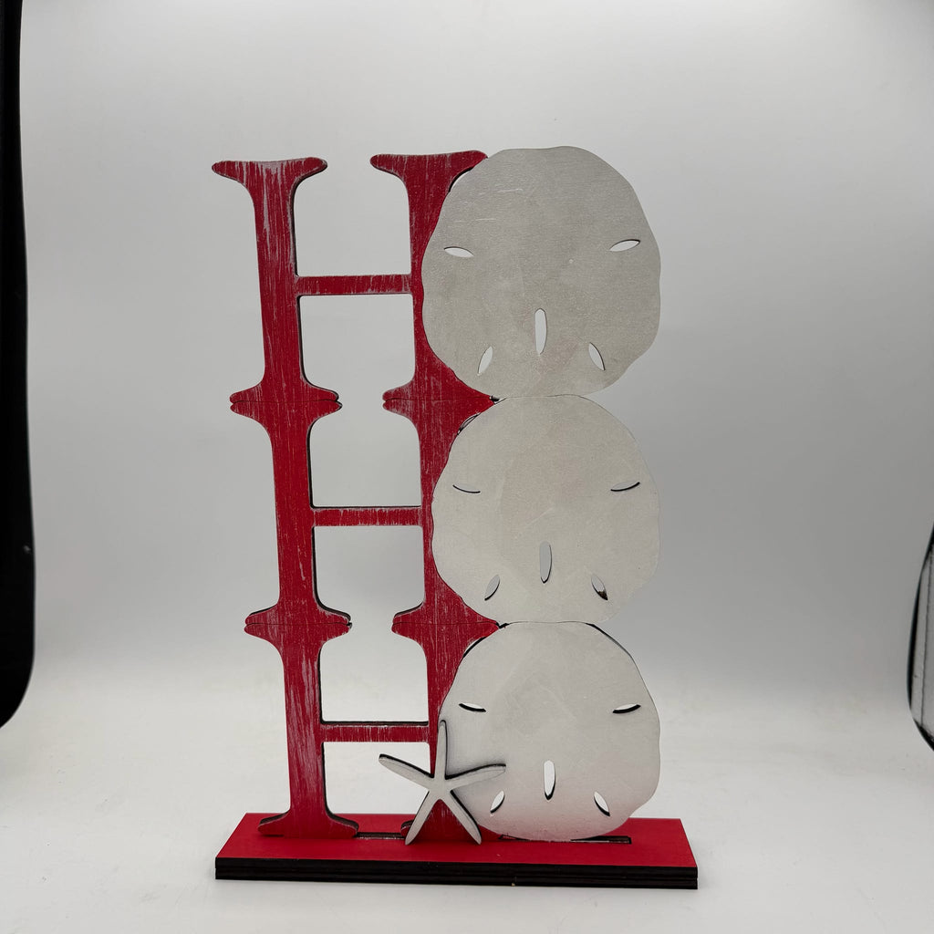 A decorative metal wall sculpture spelling out 'HOE' in distressed red, with three stacked sand dollar shapes and a small starfish on a red base, photographed against a white studio background.