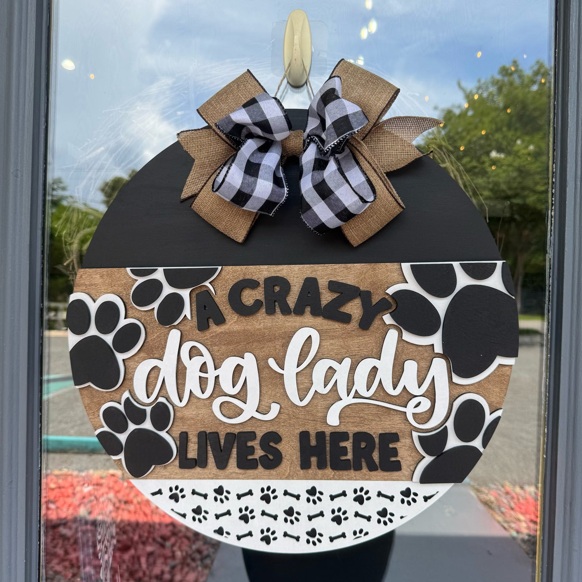 Decorative sign with 'A Crazy Dog Lady Lives Here' text and paw prints on a glass door.