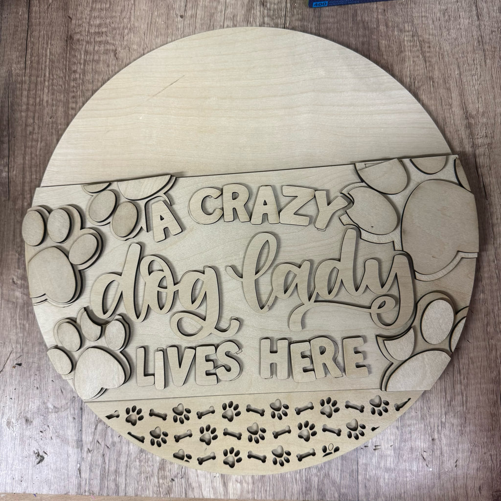 Round wooden sign with 'A crazy dog lady lives here' text on a wooden surface