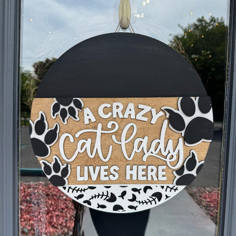 Decorative sign with 'A Crazy Cat Lady Lives Here' text on a door