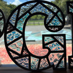 Decorative glass panel with blue and pink pebbles in a circular pattern, outdoors.