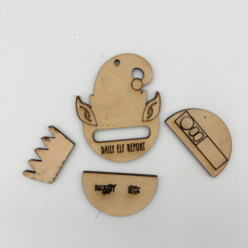 Four laser-cut wooden pieces for a daily elf report tracker, including a half-circle with a slot, a crown, a half-circle with text, and a semi-circle with icons, shown on a white background.