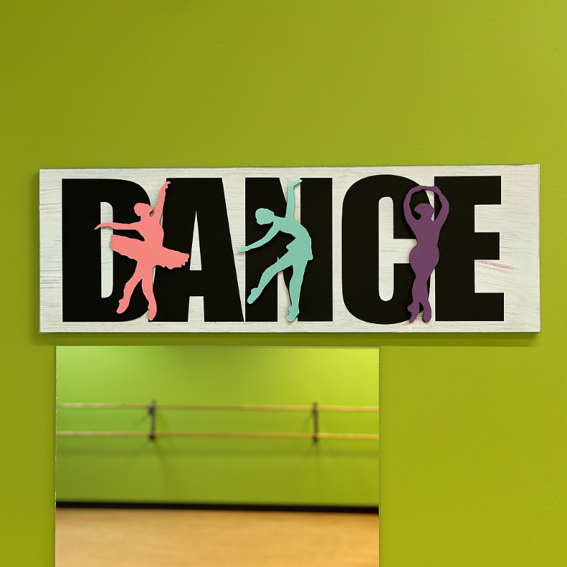 Decorative sign with 'DANCE' and silhouettes of dancers on a green wall.