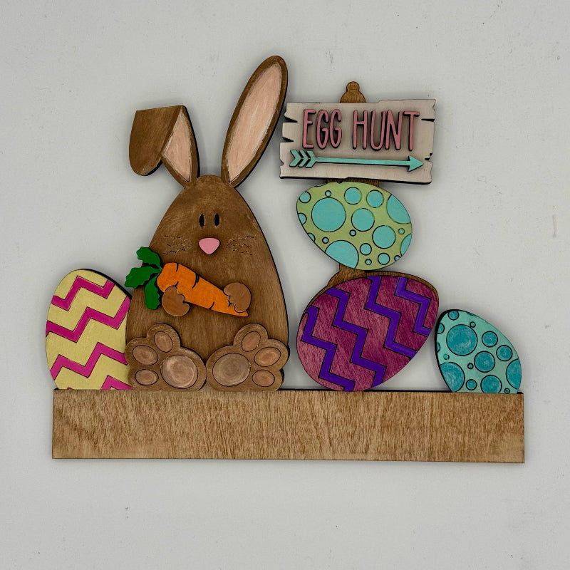 Decorative Easter sign with a rabbit, carrots, and Easter eggs on a white background