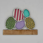 Decorative wall art with colorful circular patterns on a wooden base against a light gray background