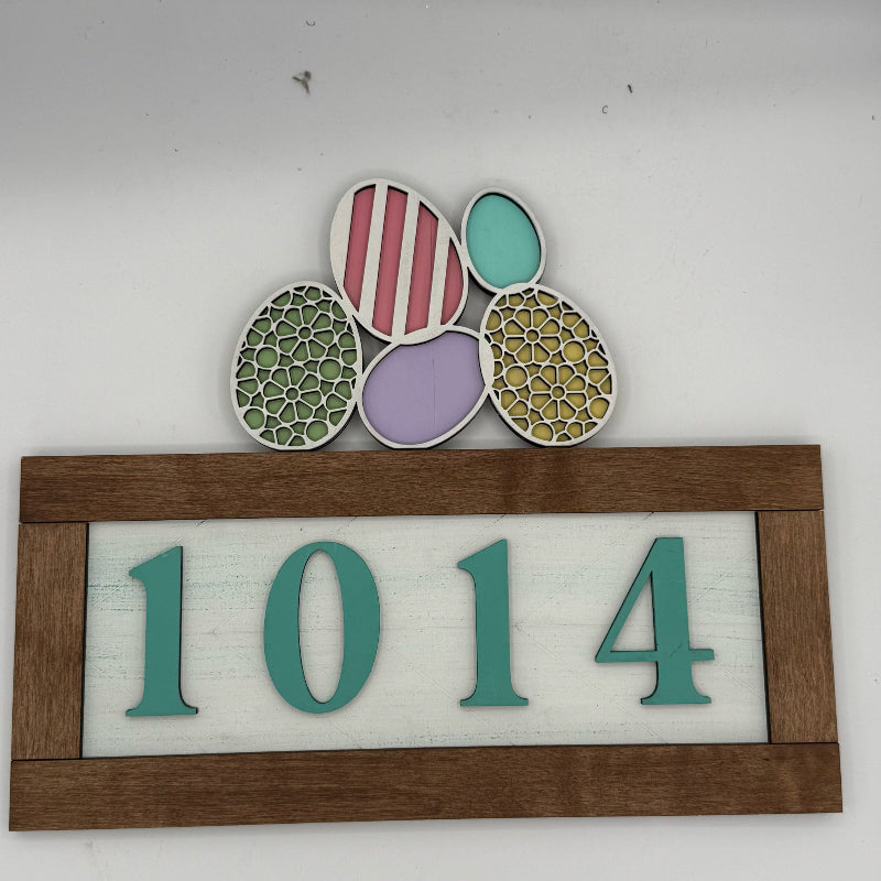 Decorative house number sign with colorful patterns and '1014' on a white background