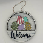 Decorative sign with colorful eggs and 'Welcome' text on a white background