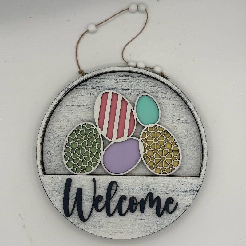 Decorative sign with colorful eggs and 'Welcome' text on a white background