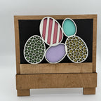 Decorative wooden box with cut-out egg shapes featuring different patterns on a white background.