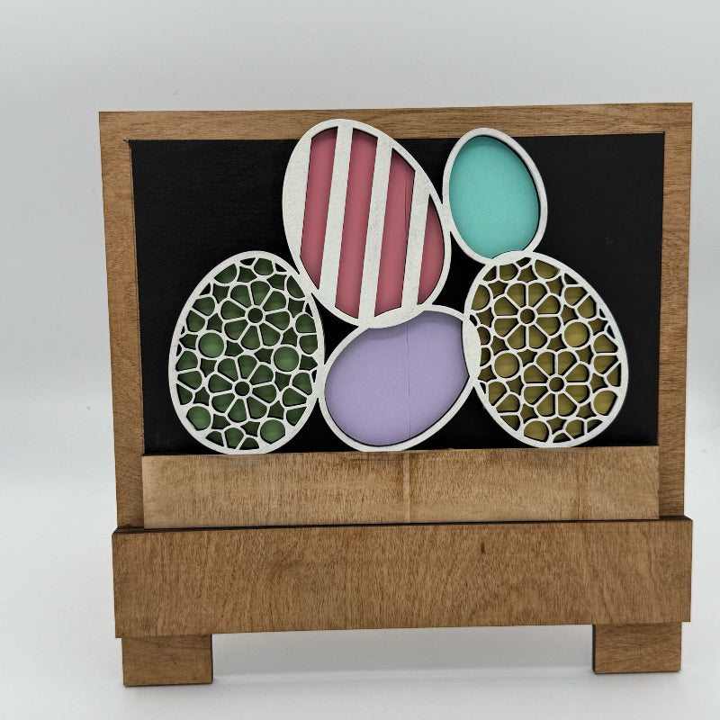 Decorative wooden box with cut-out egg shapes featuring different patterns on a white background.