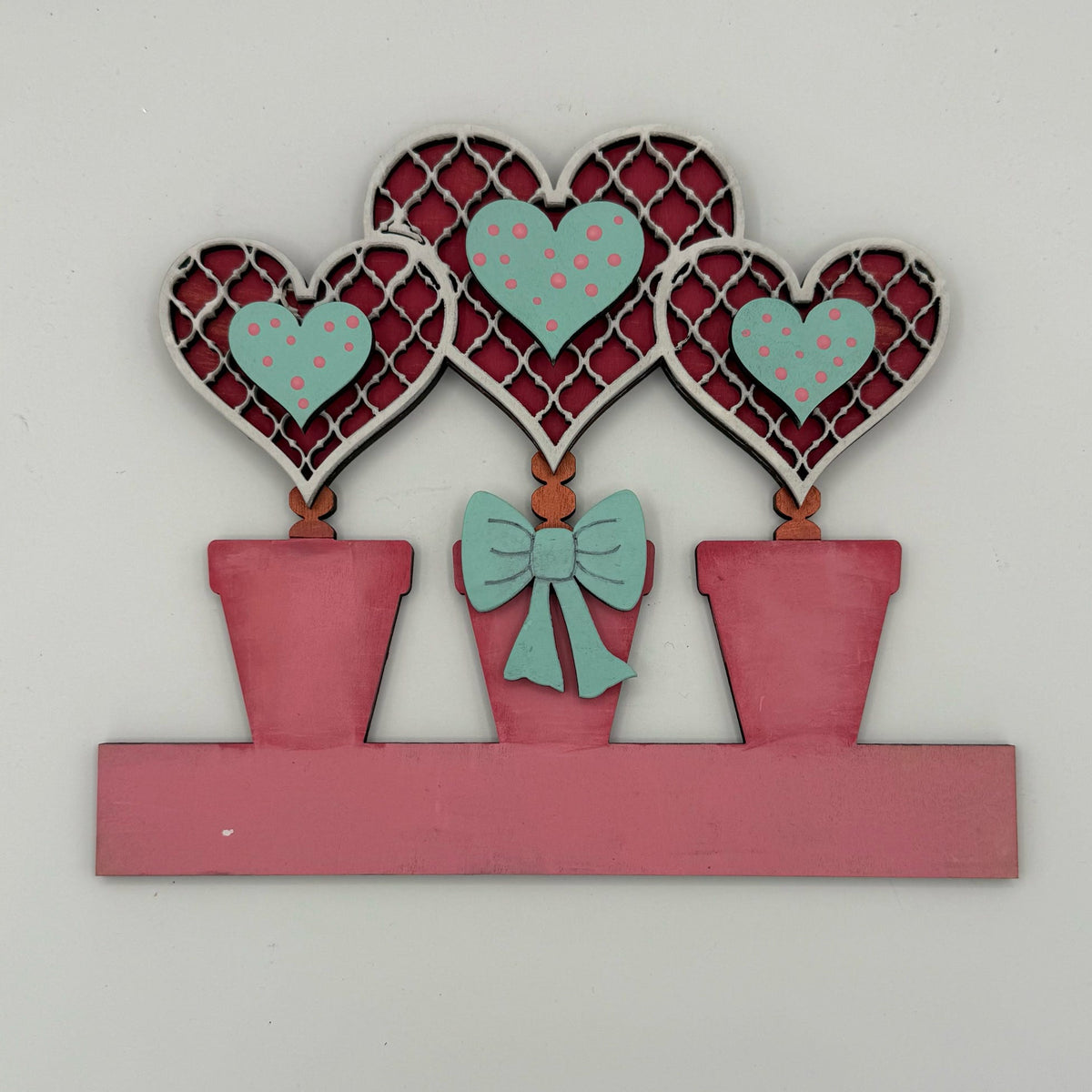Decorative wall art with hearts and a bow on a white background