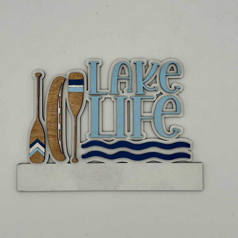 Decorative sign with 'Lake Life' text and oars on a white background