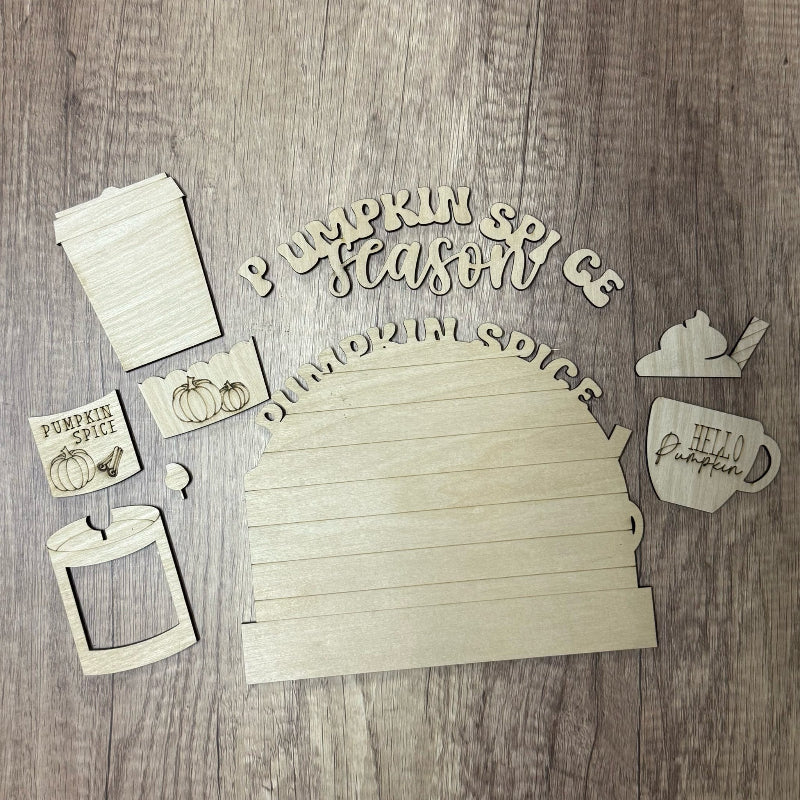 Wooden cutouts with 'Pumpkin Spice' and related designs on a wooden surface