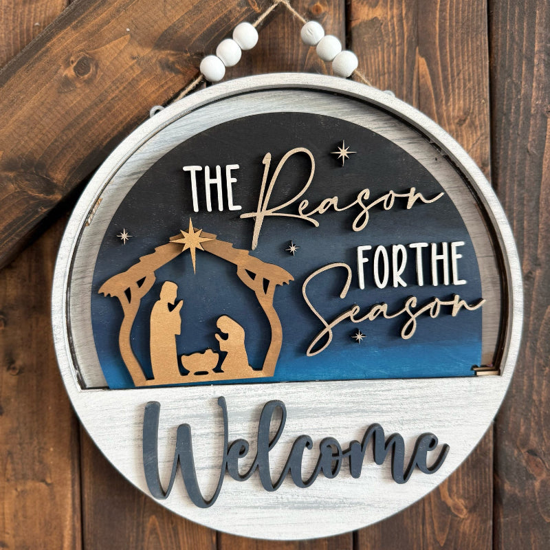 Decorative sign with nativity scene and 'The Reason For the Season Welcome' text on a wooden background.