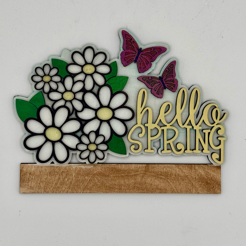 Decorative sign with flowers, butterflies, and 'hello SPRING' text on a white background
