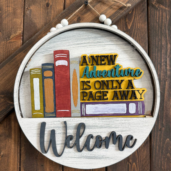 Decorative sign with books and 'Welcome' text on a wooden background