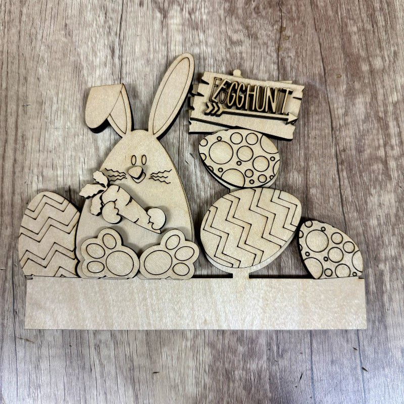 Wooden Easter decorations including a bunny, eggs, and an 'Egg Hunt' sign on a wooden surface.