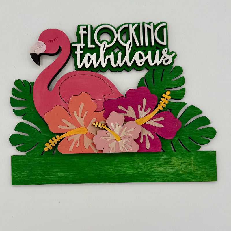 Decorative sign with pink flamingo, flowers, and 'Flocking Fabulous' text on a white background