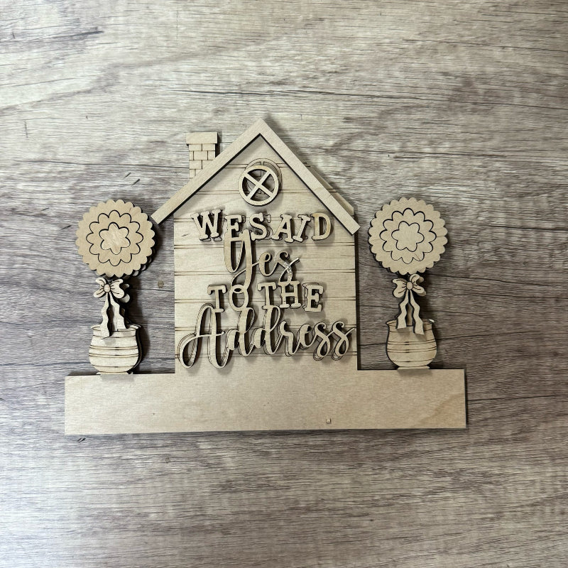Wooden decorative sign with floral designs and text on a wooden surface