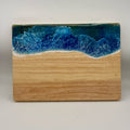 Wooden cutting board with blue resin design on a white background