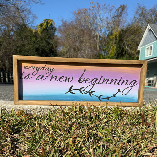 Decorative sign with 'everyday is a new beginning' text on a grassy lawn.