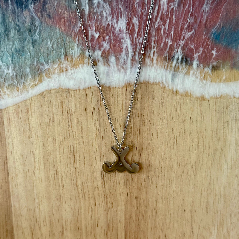 Necklace with a pendant on a wooden surface with ocean waves in the background