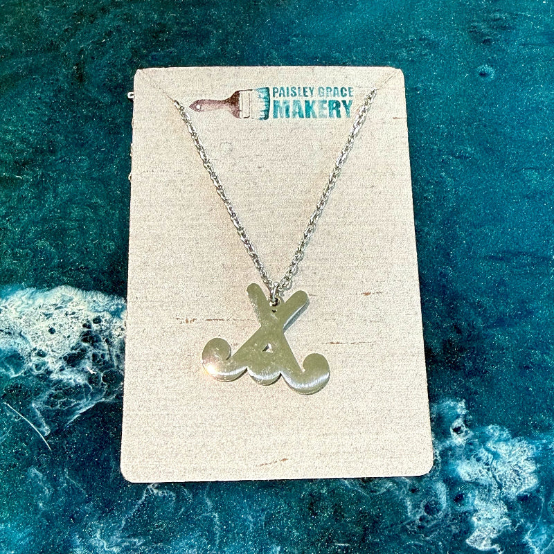 Silver necklace with a unique pendant on a branded card against a textured blue background