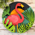 A decorative round sign featuring a pink flamingo surrounded by green foliage.