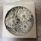 Laser-cut wooden card with floral design on a wooden surface
