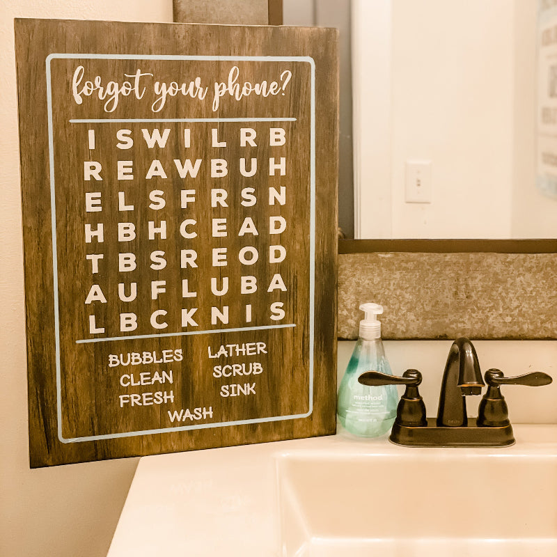Wooden sign with text over a sink in a bathroom