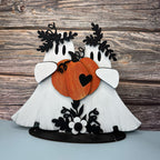 Decorative piece with two white birds holding pumpkins on a wooden background