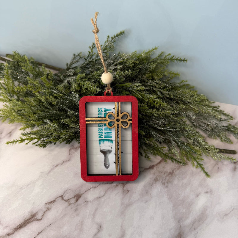 Decorative Christmas ornament with a cross design on a marble surface with greenery.
