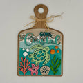 Decorative sign with turtle, fish, and text on a wooden board with a white background