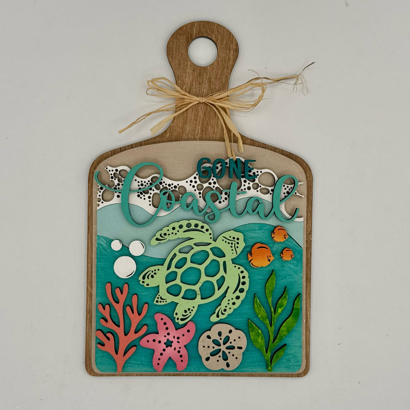 Decorative sign with turtle, fish, and text on a wooden board with a white background