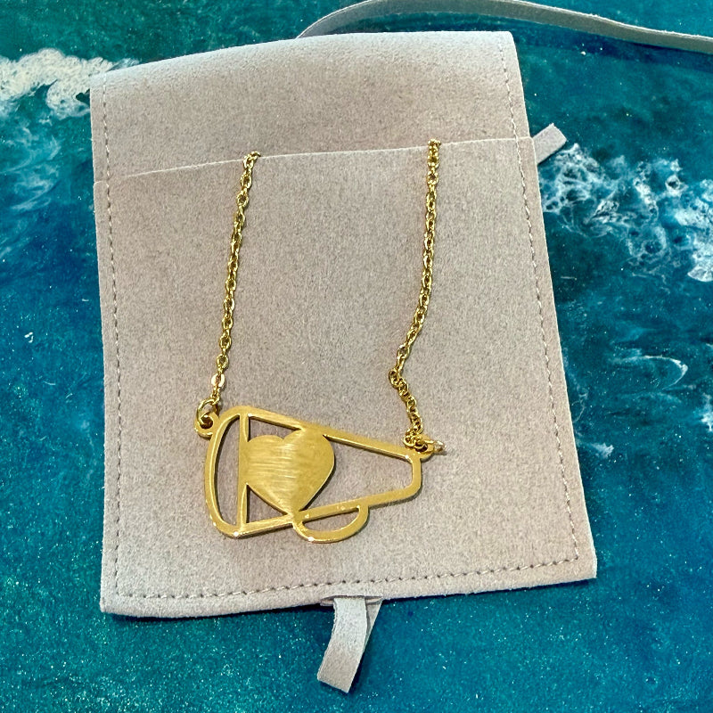 Gold necklace with a heart design on a beige card against a blue textured background