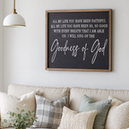 Living room with a beige sofa, decorative pillows, a candle, and a framed Christian quote on the wall.